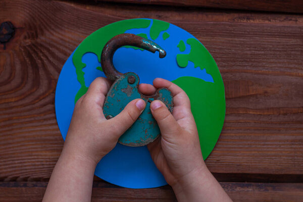 Lockdown is over creative concept, open iron lock in child 's hands on wooden background. Открытие границ между странами. Завершение карантина COVID19, возвращение к нормальной жизни.
