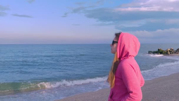 Девушка Длинными Волосами Розовой Толстовке Синего Моря Видом Песчаный Пляж — стоковое видео