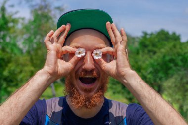 Sakallı adam elinde çiçeklerle yeşil orman arka planındaki gözler gibi. Uzun kızıl sakallı, duygusal suratlı komik bir hippi. Doğal ortamda çılgın, olgun bir adam. Yaz eğlencesi erkek eğlencesi.