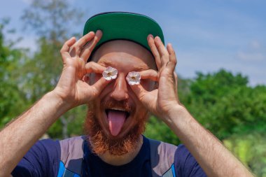 Sakallı adam elinde çiçeklerle yeşil orman arka planındaki gözler gibi. Uzun kızıl sakallı, duygusal suratlı komik bir hippi. Doğal ortamda çılgın, olgun bir adam. Yaz eğlencesi erkek eğlencesi.