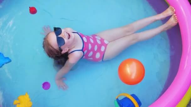 분홍색 수영복을 소녀가 뒷마당에 수영장에서 있습니다 국내에서의 활동적 생활은 아이들을 — 비디오