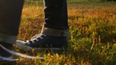 Ayakkabı bağcıklarını bağlayan ve ormanda koşan birine yaklaş. Açık havada spor sporu yapmak. Kot ayakkabılı buzağılar orman yolunda yürüyor. Ayakkabılarını bağla. Bağcıklarını çim üzerinde çöz