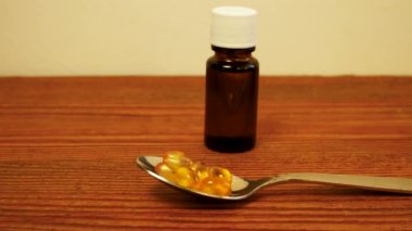 Çocuklar ve yetişkinler için D vitamini şişesi. D3 vitamini damlaları. Omega-3 takviyeli kapsüller masada duran kaşıkta saydam sarı toplar. Cam düşürücü şişe maketi. Sağlık hizmetleri