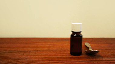 Çocuklar ve yetişkinler için D vitamini şişesi. D3 vitamini damlaları. Masadaki kaşıkta saydam sarı toplar bulunan balık yağı Omega-3 takviyeli ilaçlar. Cam düşürücü şişe. Sağlık hizmetleri.