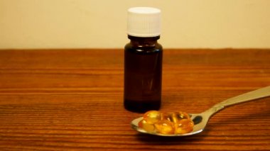 Çocuklar ve yetişkinler için D vitamini şişesi. D3 vitamini damlaları. Omega-3 takviyeli kapsüller masada duran kaşıkta saydam sarı toplar. Cam düşürücü şişe maketi. Sağlık hizmetleri