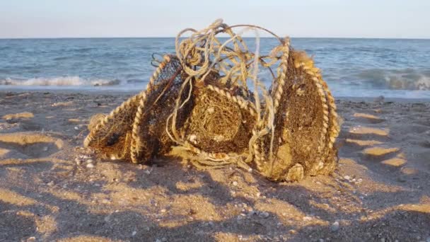 古い錆びたワイヤーで汚れた漁網を使用し ゴミは海の砂浜に捨てられました 環境汚染問題の概念 砂の海岸だ 青い水の背景に波を移動します ボランティアコンセプト — ストック動画