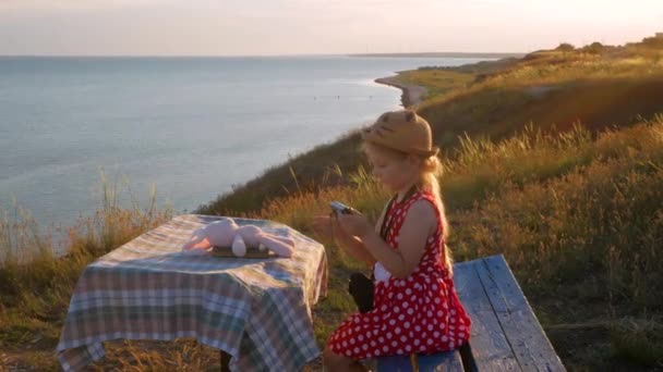 Barnflicka Halmhatt Och Klänning Sitter Vintage Bänk Och Tar Bild — Stockvideo