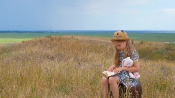 Hasır Şapkalı Elbiseli Çocuk Klasik Bir Bavula Oturmuş Kitap Okuyor — Stok video