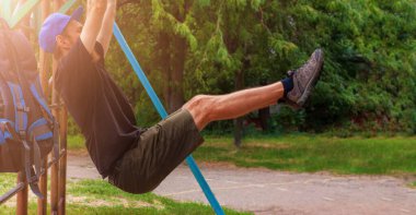 Sporcu, barfiks çekiyor. Erkek sporcu, teneffüste dışarıda oyun alanında spor yapıyor. Sırt çantalı sakallı genç adam iş gününden sonra ısınıyor. Etkin yaşam biçimi.