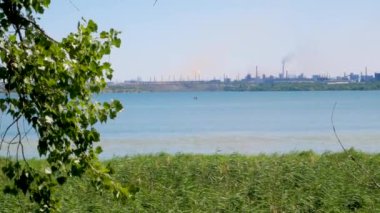 Fabrika borularından mavi gökyüzünün aksine büyük kalın beyaz ve siyah dumanların döküldüğü sanayi bölgesi. Çevre kirliliği. Güneşli bir günde şehrin nehir suyunun üzerinde fabrika bacası.