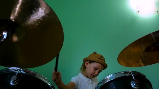 在音乐学校学习鼓的孩子 黑鼓套件有鼓手的小音乐家鼓手用绿色墙壁背景的画笔进行训练 带着帽子的金发小女孩在课堂上玩耍和微笑 — 图库视频影像