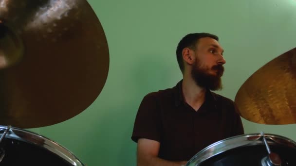 鼓手用鼓刷热身 留胡子的男人在绿墙背景下 用鼓声弹奏摇滚和金属乐 乐队彩排干扰4K段画面 — 图库视频影像