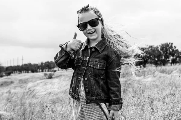 Imádnivaló Kislány Farmerdzsekiben Napszemüvegben Kék Kockás Ruhában Fűmezőn Boldog Elegáns — Stock Fotó