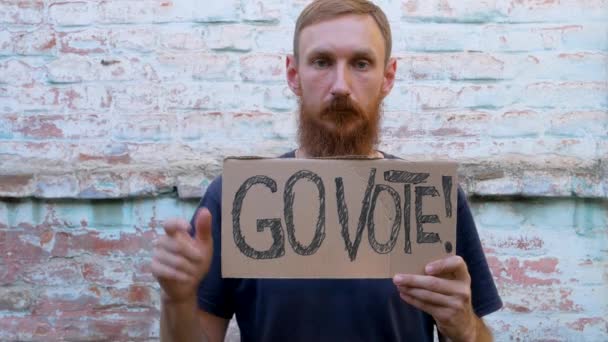 Hombre Muestra Cartulina Con Vote Signo Pared Ladrillo Fondo Urbano — Vídeo de stock