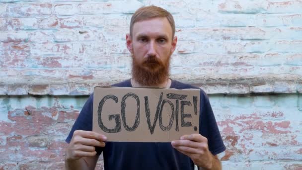 Mann Zeigt Pappe Mit Vote Zeichen Auf Backsteinmauer Städtischen Hintergrund — Stockvideo