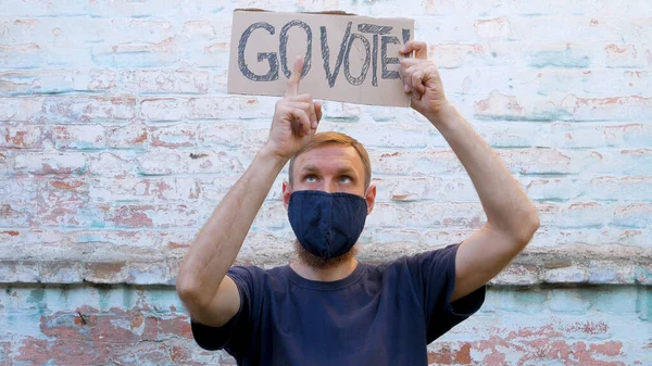 Hombre Muestra Cartulina Con Vote Signo Pared Ladrillo Fondo Urbano —  Fotos de Stock