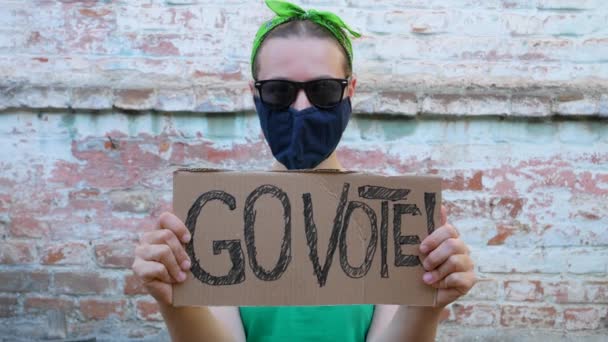 女人们在砖墙的城市背景上展示带有 使用你的声音 标志的纸板 表决概念 做出政治选择 去投票 戴黑太阳镜的女士要去参加总统选举 — 图库视频影像