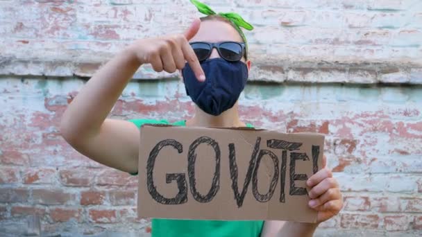 女人们在砖墙的城市背景上展示带有 使用你的声音 标志的纸板 表决概念 做出政治选择 去投票 戴黑太阳镜的女士要去参加总统选举 — 图库视频影像