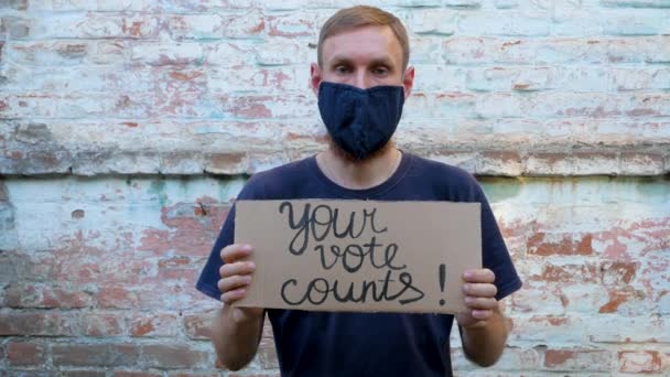 Homem Mostra Papelão Com Sinal Vote Parede Tijolo Fundo Urbano — Vídeo de Stock