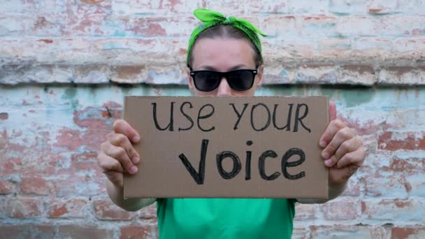 Vrouw Toont Karton Met Use Your Voice Teken Bakstenen Muur — Stockvideo