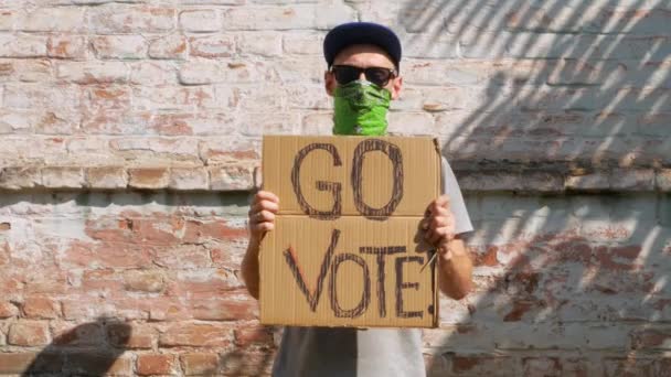 Mann Zeigt Pappe Mit Vote Zeichen Auf Backsteinmauer Städtischen Hintergrund — Stockvideo