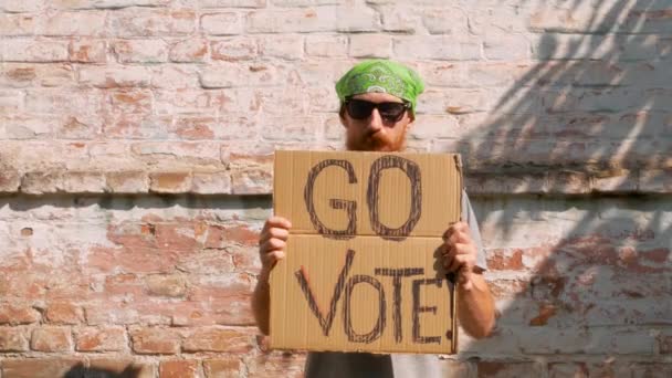 Hombre Muestra Cartulina Con Vote Signo Pared Ladrillo Fondo Urbano — Vídeos de Stock