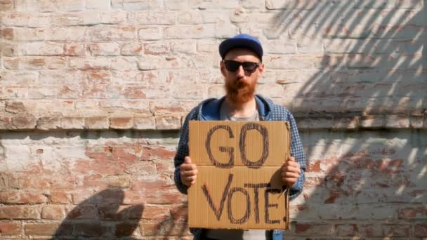 Mann Zeigt Pappe Mit Vote Zeichen Auf Backsteinmauer Städtischen Hintergrund — Stockvideo