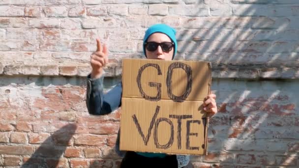 Mulher Mostra Papelão Com Vote Sinal Parede Tijolo Fundo Urbano — Vídeo de Stock