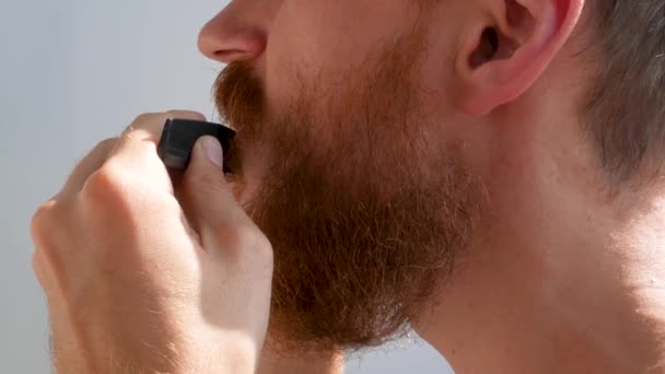 成年人用剪刀和梳子修剪自己的胡子和胡子 在家里 白种人的红胡子男人在脸上修剪头发 你自己做吧 隔离期间的自理死亡 — 图库视频影像