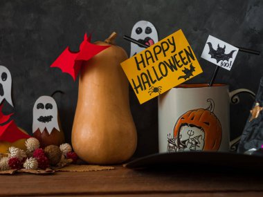 Sosyal medya için arka planda kahve fincanı, balkabağı, sonbahar yaprakları ve çiçeklerle yaratıcı Mutlu Cadılar Bayramı kompozisyonu. Tatil kutlaması duvar kâğıdı. Çay fincanı komik tebrik tabelaları ve kağıt yarasalar..