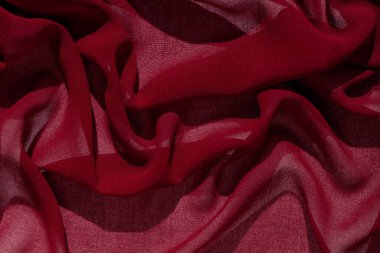 Pürüzsüz, burgundy şifon kumaş, soyut bir arka plan. Koyu kırmızı şarap ipek kumaş. Tasarım için açık yüzey üzerinde lüks kumaş. Lüks Sevgililer Günü arkaplanı. Dalgalı mat dokulu malzeme
