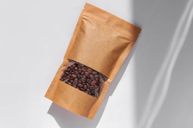 Kahverengi kese kağıtları kahve çekirdekli çantalar beyaz arka planda gölgelenmiş gölgeler. Yiyecek ve ürün şablonları için ambalaj mockup.Tokalı ve çay için pencereli paketler ağırlık bırakır