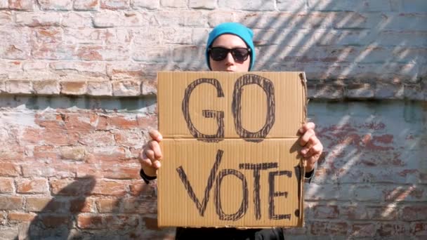 Mulher Mostra Papelão Com Vote Sinal Parede Tijolo Fundo Urbano — Vídeo de Stock