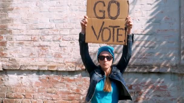 Mulher Mostra Papelão Com Vote Sinal Parede Tijolo Fundo Urbano — Vídeo de Stock