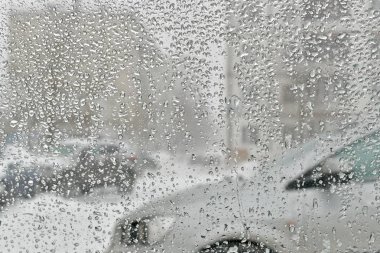 Damla kar penceresinde erime üzerinden. Karlı avlu görünümü.