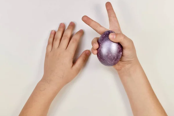 Mâinile copiilor joacă iepurașul de Paști cu un ou violet . — Fotografie, imagine de stoc