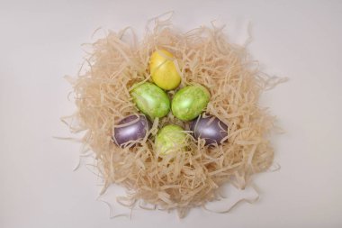 Hafif bir arka planda renkli Paskalya yumurtaları ile yuvarlak dalgalı yuva. Yumuşak ışıkta üst görünüm.