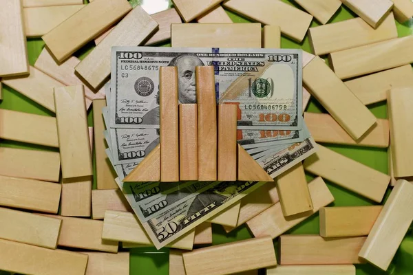 Investing in stock exchanges. The graph of the fall and rise, built on dollar bills, in a box with a wooden constructor.