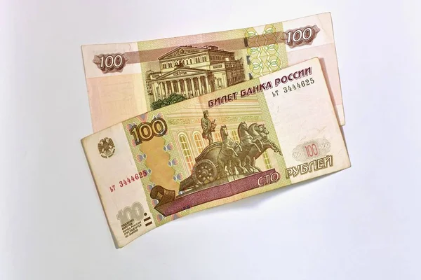 100 rubli ułożone na siebie. Dwa banknoty. Jedna twarz, druga odwrotna. Leżą w środku na lekkiej powierzchni. — Zdjęcie stockowe