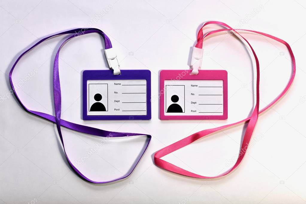 Two blank badges, pink and purple, with satin ribbons for wearing around the neck. On a light background next to each other in the center.