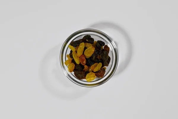 Rosinen, dunkel und hell, in runder Form. getrocknete Trauben in einer kleinen Menge. Draufsicht, mittig, auf weißem Hintergrund. — Stockfoto