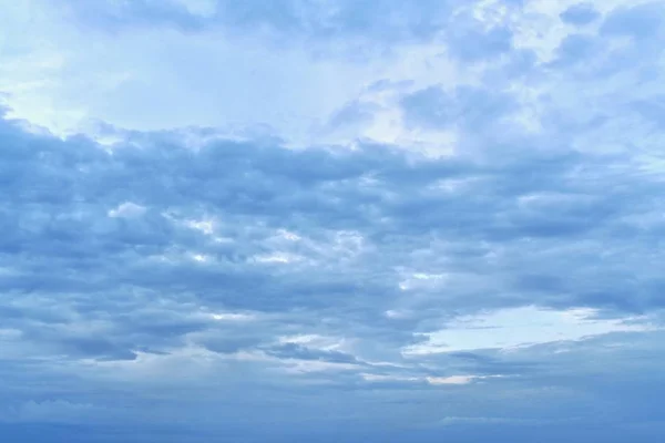 Cielo azul con nubes azules oscuras. Arriba, por encima de las nubes, el área brillante a la izquierda. A continuación hay nubes más alargadas, horizontalmente más concurridas en el centro . — Foto de Stock