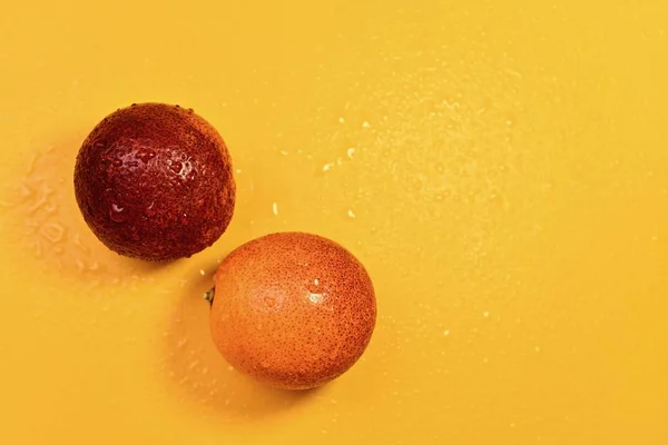 Um par de laranjas vermelhas em um fundo amarelo . — Fotografia de Stock