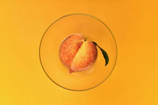 Pêssego fresco em uma tigela transparente em um topo amarelo . — Fotografia de Stock