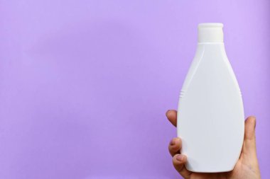 Bir elinde yazıt olmadan kozmetik şişe.