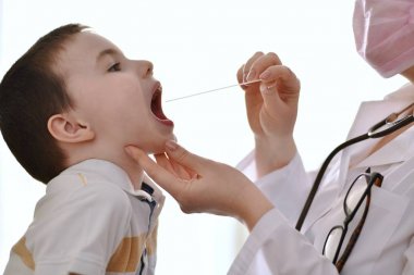 Doctor examines the throat of a child. clipart