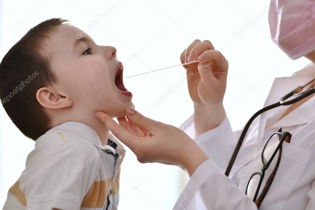 Doctor examines the throat of a child.