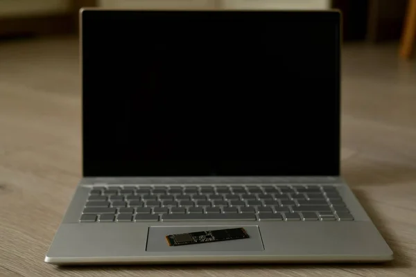 SSD накопичувач на відкритому ноутбуці на дерев'яній поверхні . — стокове фото