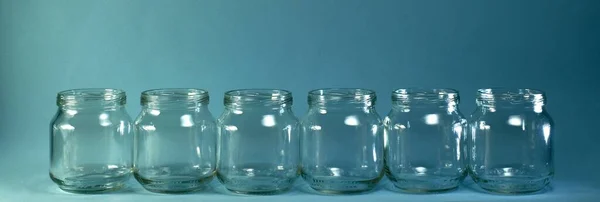 Horizontal row of transparent jars on a blue background with a wide baner. — Stock Photo, Image