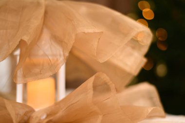 Dekoratif, aydınlık bir fener, altında ve üstünde şenlikli bir örtüyle süslenmiş, karanlığa bürünmüş bir Noel ağacının arka planında aydınlık bir yılbaşı çelengiyle..